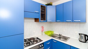 A kitchen with blue cabinets, a gas stove, a sink, and a kettle. - Apartments Villa Ana - Dingac (Orebic)