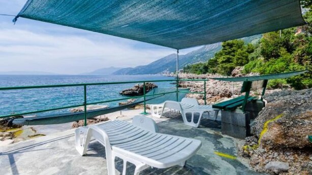 A seaside terrace with white plastic chairs and a green metal railing overlooking the sea. - Apartments Villa Ana - Dingac (Orebic)