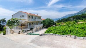 A two-story building with a balcony, surrounded by greenery and mountains. - Apartments Villa Ana - Dingac (Orebic)