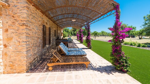 A stone building with a covered outdoor seating area, including wooden loungers and a pergola. - PARATGE DE SON TONIET - Apartment with private pool in Buger. Free WiFi (B��ger)
