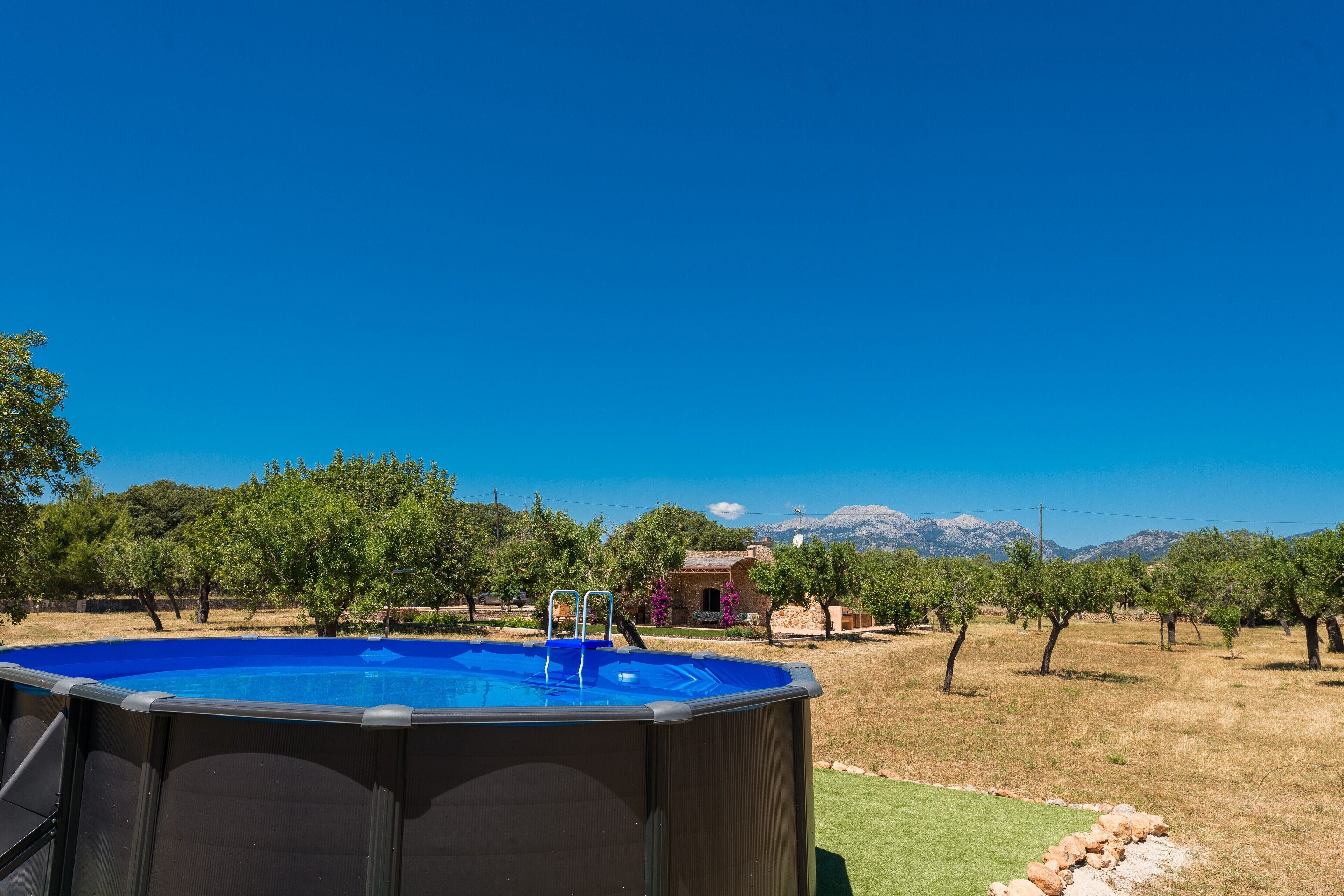 Ein Schwimmbecken mit Blick auf ein Haus und Berge im Hintergrund.