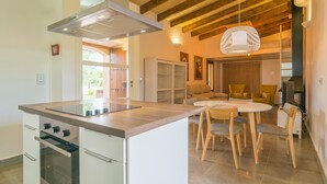 A modern kitchen with a central island, built-in oven, and a dining area with a round table and chairs. - PARATGE DE SON TONIET - Apartment with private pool in Buger. Free WiFi (B��ger)