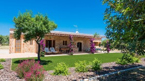 A stone house with a patio, surrounded by a well-maintained lawn and flowering plants. - PARATGE DE SON TONIET - Apartment with private pool in Buger. Free WiFi (B��ger)