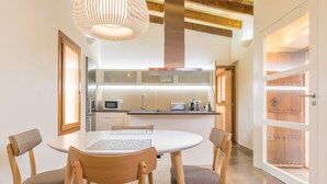 A modern kitchen with a round dining table, wooden chairs, and a pendant light. - PARATGE DE SON TONIET - Apartment with private pool in Buger. Free WiFi (B��ger)