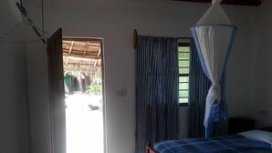 Un dormitorio con cama, ventana con cortinas, puerta que da al exterior y lámpara colgante.