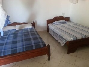 A room with two wooden beds, each with a different patterned bedspread.