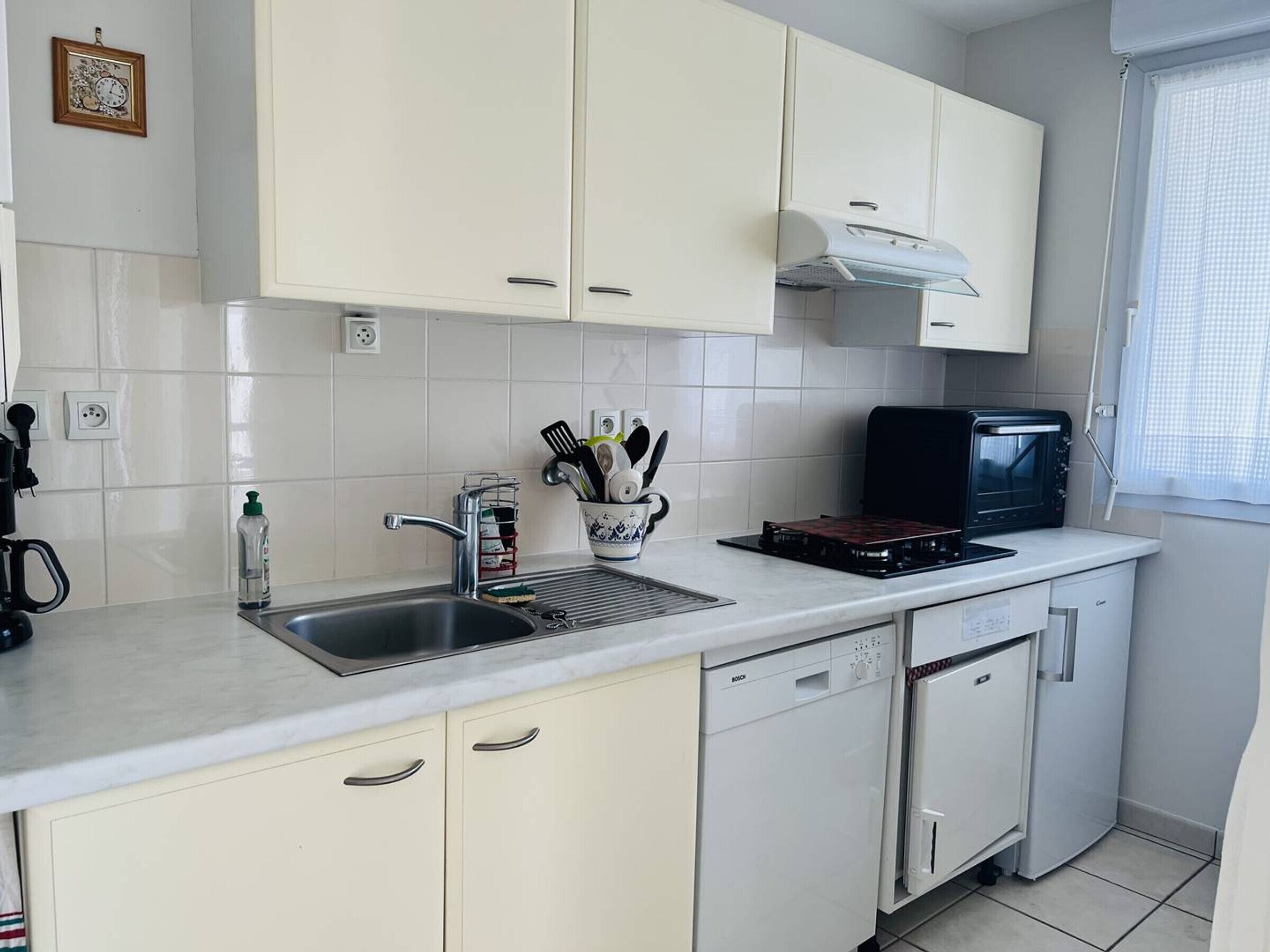 A compact kitchen with white cabinets, a sink, a microwave, and a dishwasher.