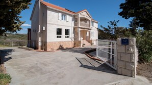 Una casa de dos pisos con techo rojo, un balcón y una entrada protegida por una reja.
