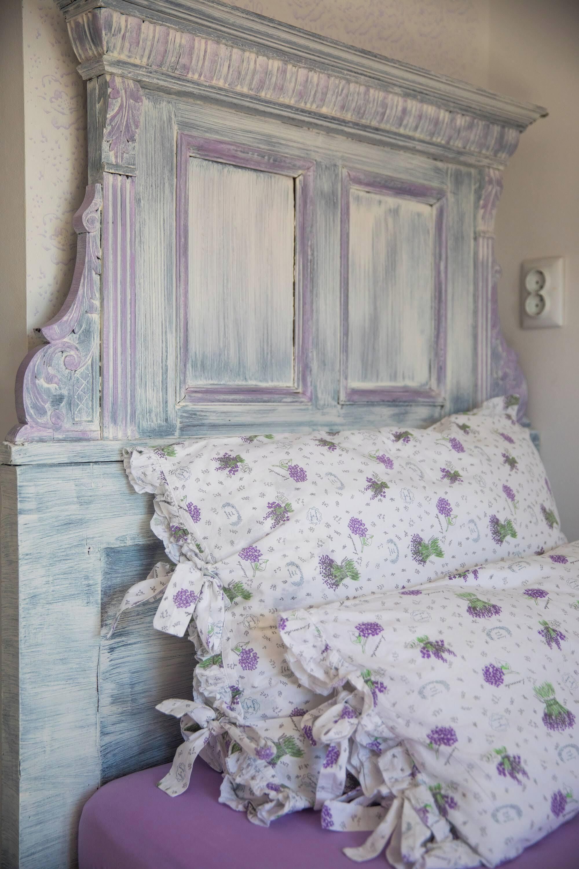 En seng med et blomstret sengetæppe og en sengestol i vintage stil.