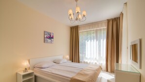 A bedroom with a bed, bedside tables, a lamp, a mirror, and a window with curtains. - Varna South Bay Apart Complex (Varna)