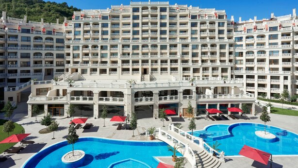 A hotel with multiple balconies, a swimming pool, and a landscaped area with umbrellas. - Varna South Bay Apart Complex (Varna)