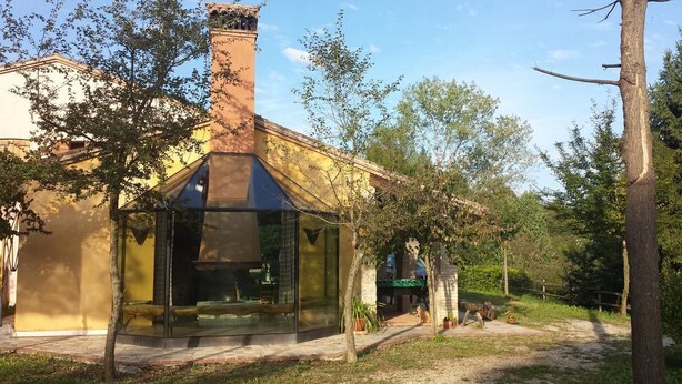 A modern building with a glass enclosure, surrounded by trees and a clear sky. - La Valle (Giavera del Montello)
