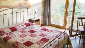 A bedroom with a metal bed frame, a quilted bedspread, a bedside table, and a chair. - La Valle (Giavera del Montello)