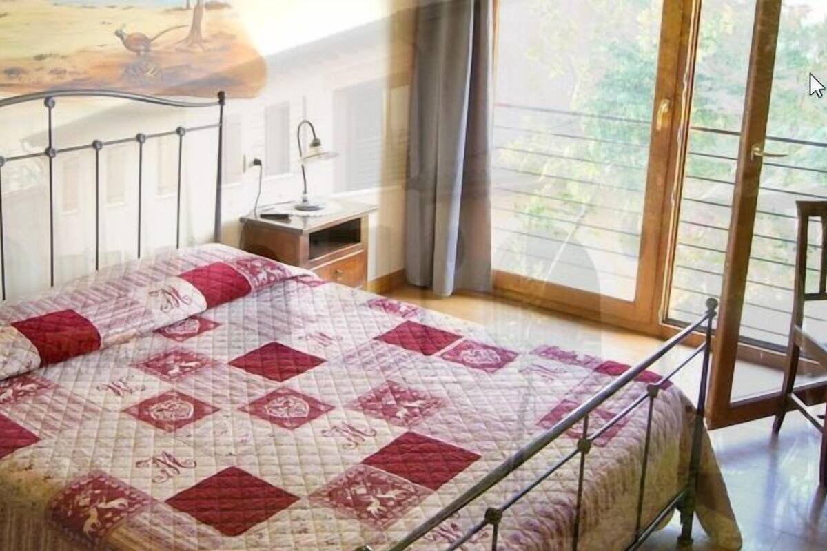 Une chambre à coucher avec un lit en métal, une couvre-lit matelassée, une table de chevet et une chaise.