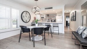 Una cucina moderna con isola centrale, mobili bianchi e schienale geometrico.