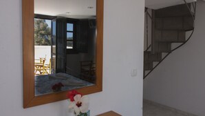 A room with a wooden desk, a mirror, and a vase with flowers. - Dagris Villa Studios (Santorini)