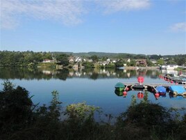 Un lago tranquilo con casas en la orilla y un muelle con barcos.