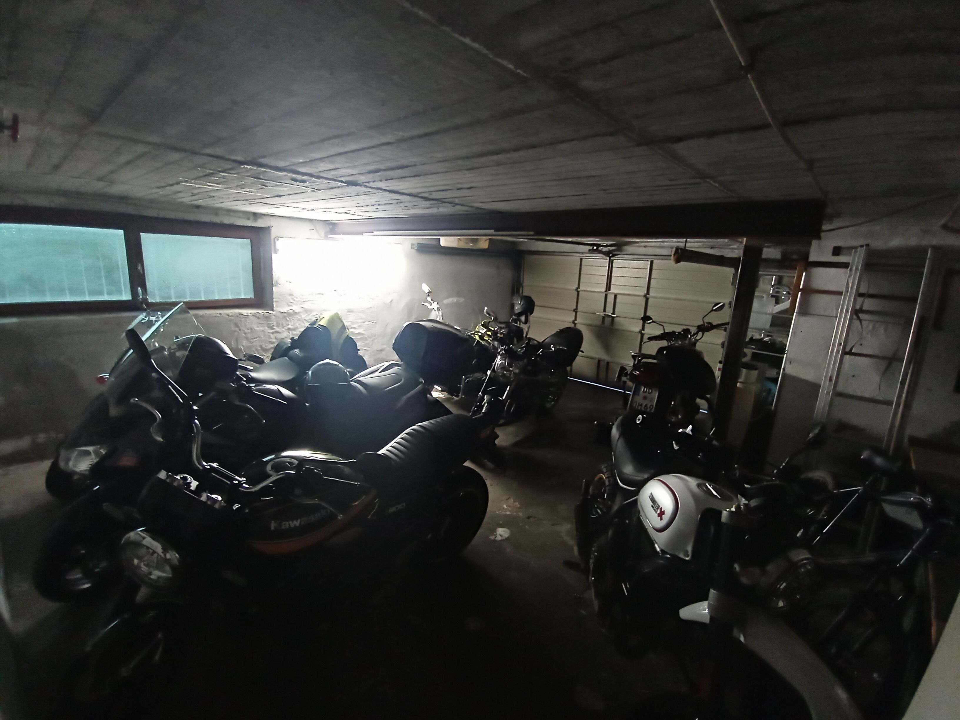 Un garaje tenuemente iluminado con varias motocicletas estacionadas.