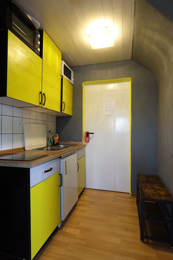 A compact kitchen with yellow cabinets, a microwave, and a sink.