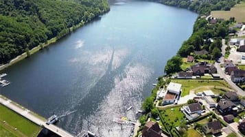 Een luchtbeeld van een rivier met een brug, omringd door weelderige begroeiing en woongebouwen.