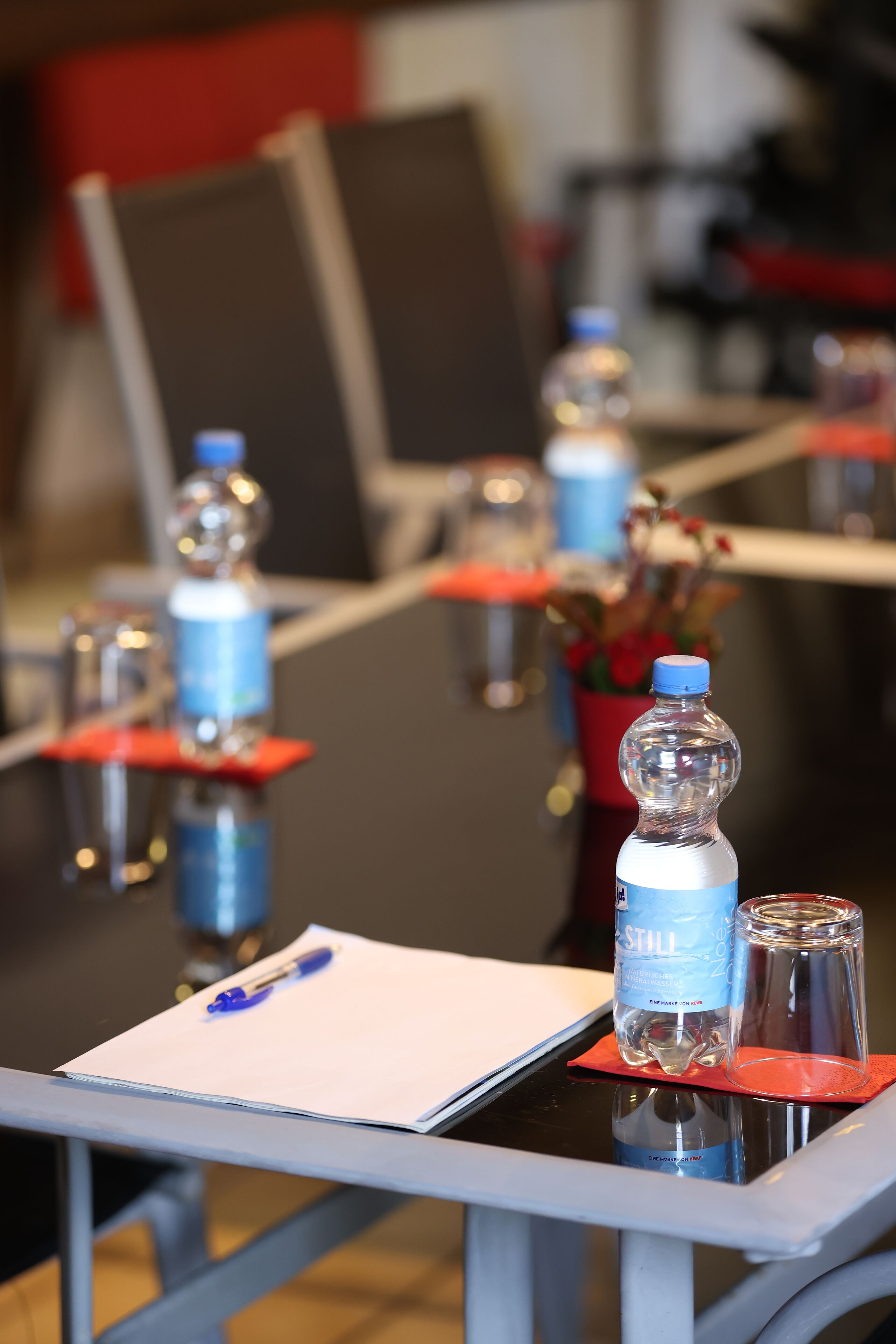 Una mesa de conferencias con botellas de agua, un bolígrafo y una libreta.