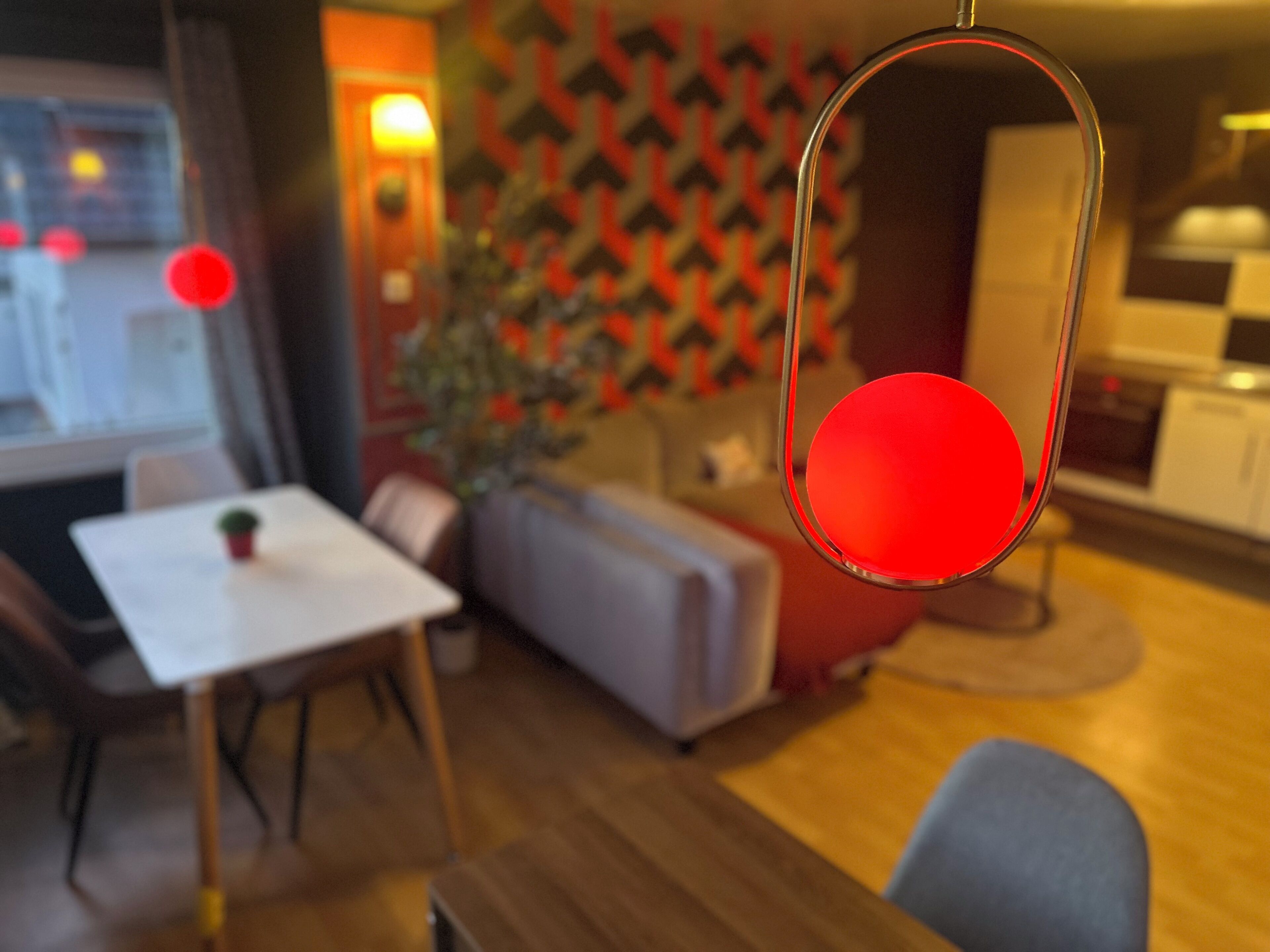 Una sala moderna con comedor, un sofá, una mesa de centro y una lámpara colgante roja.