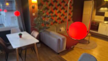Una sala moderna con comedor, un sofá, una mesa de centro y una lámpara colgante roja.