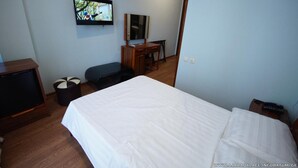 Una habitació d'hotel amb un llit, escriptori, cadira, televisió i una taula petita.