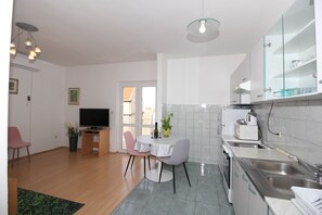 Una cocina moderna con comedor, televisor y una planta en maceta.