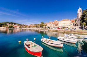 Overlooking a serene harbor, this property offers stunning views of boats moored in calm waters and a historic town with a prominent church tower.
