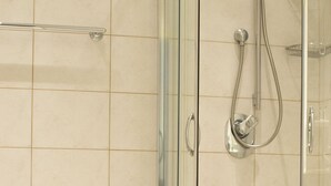 Een moderne badkamer met een douchecabine, een wit bad en een toilet.