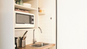 A kitchen with a microwave, sink, and wooden countertop. - Souplex - 4P - Batignolles (Paris)