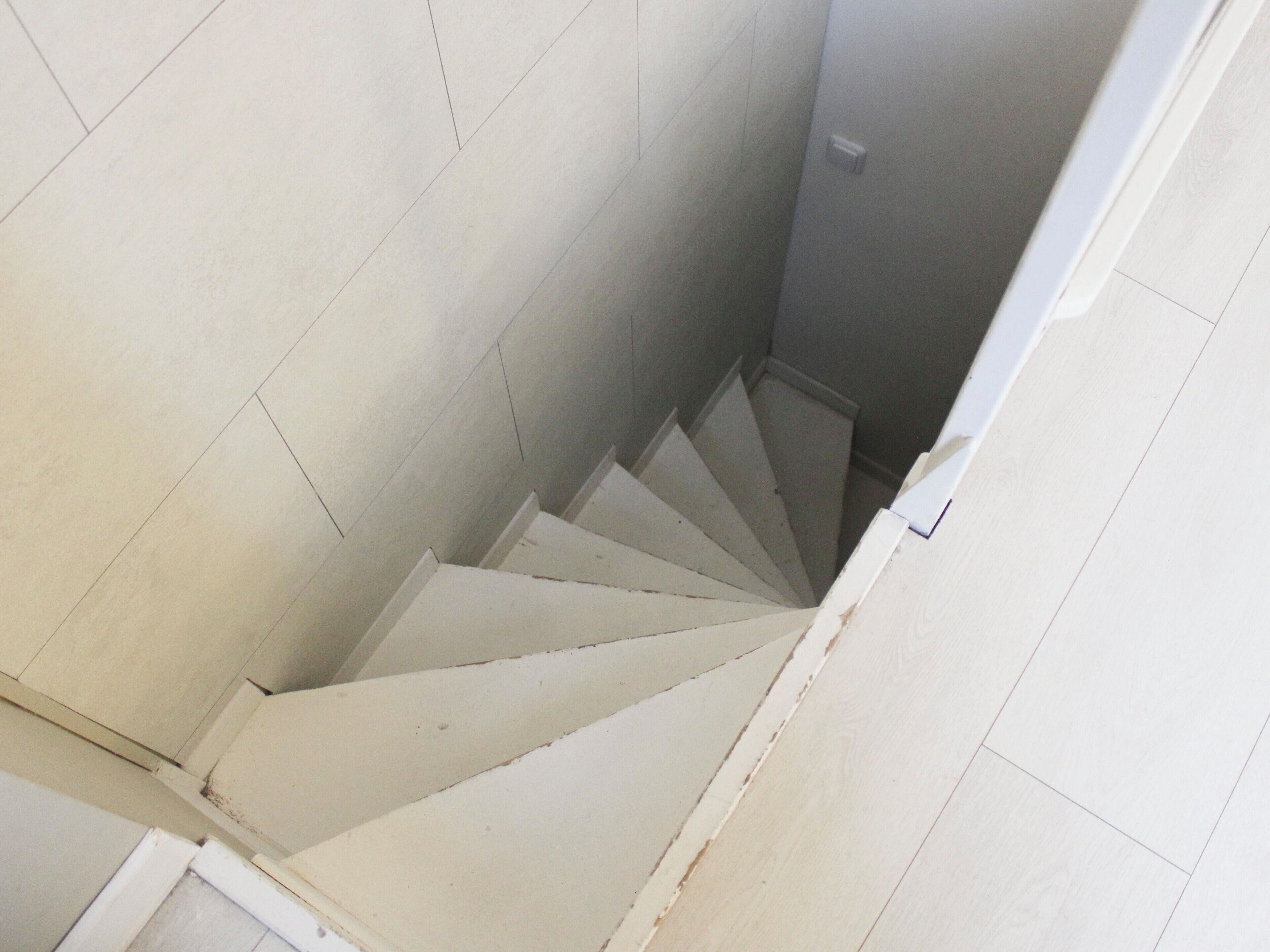 Una escalera con paredes blancas y una puerta blanca al final.
