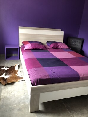 A bed with a wooden frame and a purple and pink checkered bedspread. - House villas with swimming pool on Nîmes (Nîmes)