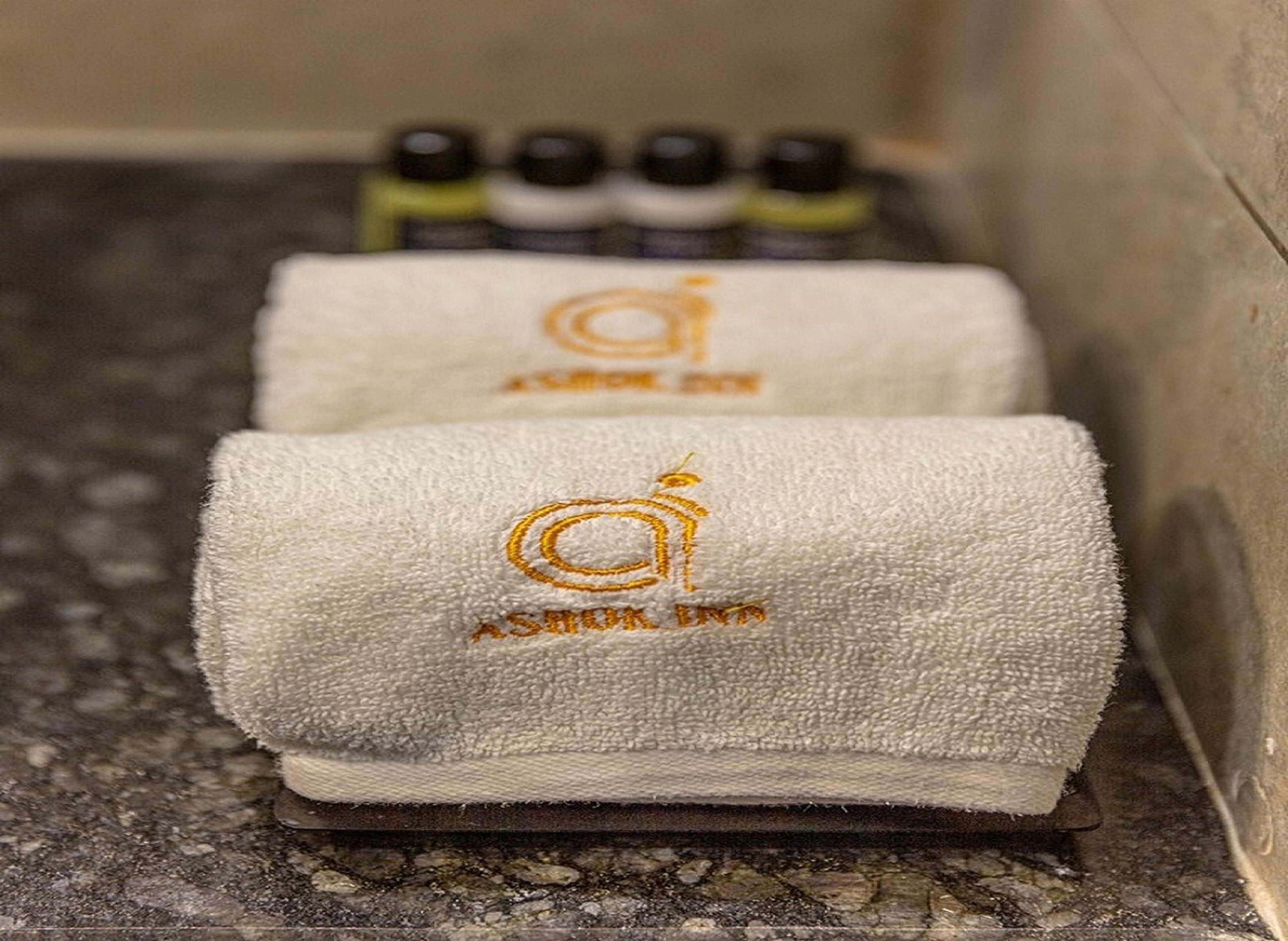 Two folded towels with embroidered logos on a textured surface.