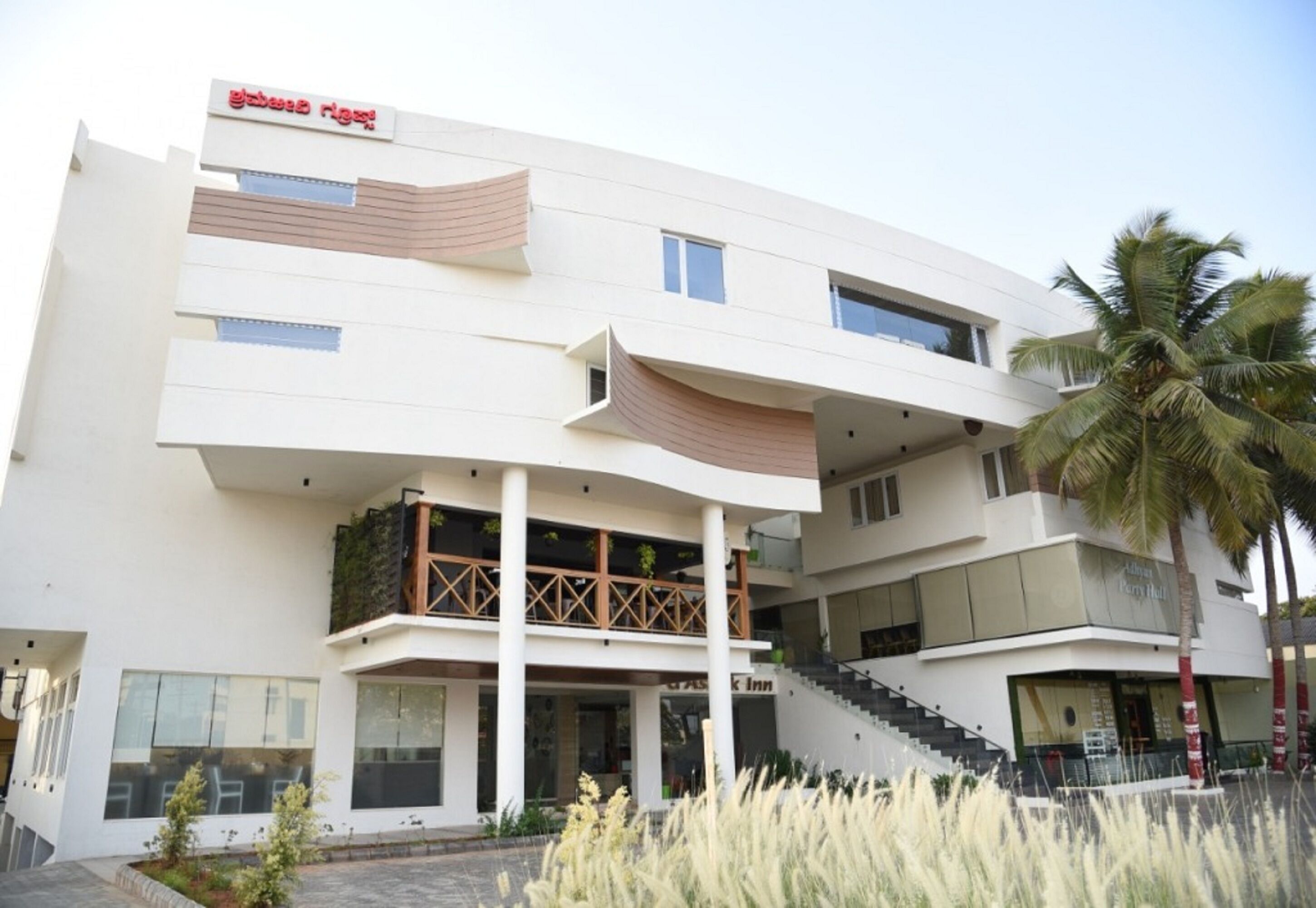 Ein modernes Hotel mit flachem Dach, mehreren Balkonen und einer Treppe, die zu den oberen Stockwerken führt.