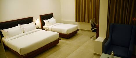 Een hotelkamer met twee bedden, een tafeltje, een stoel en een plafondventilator.