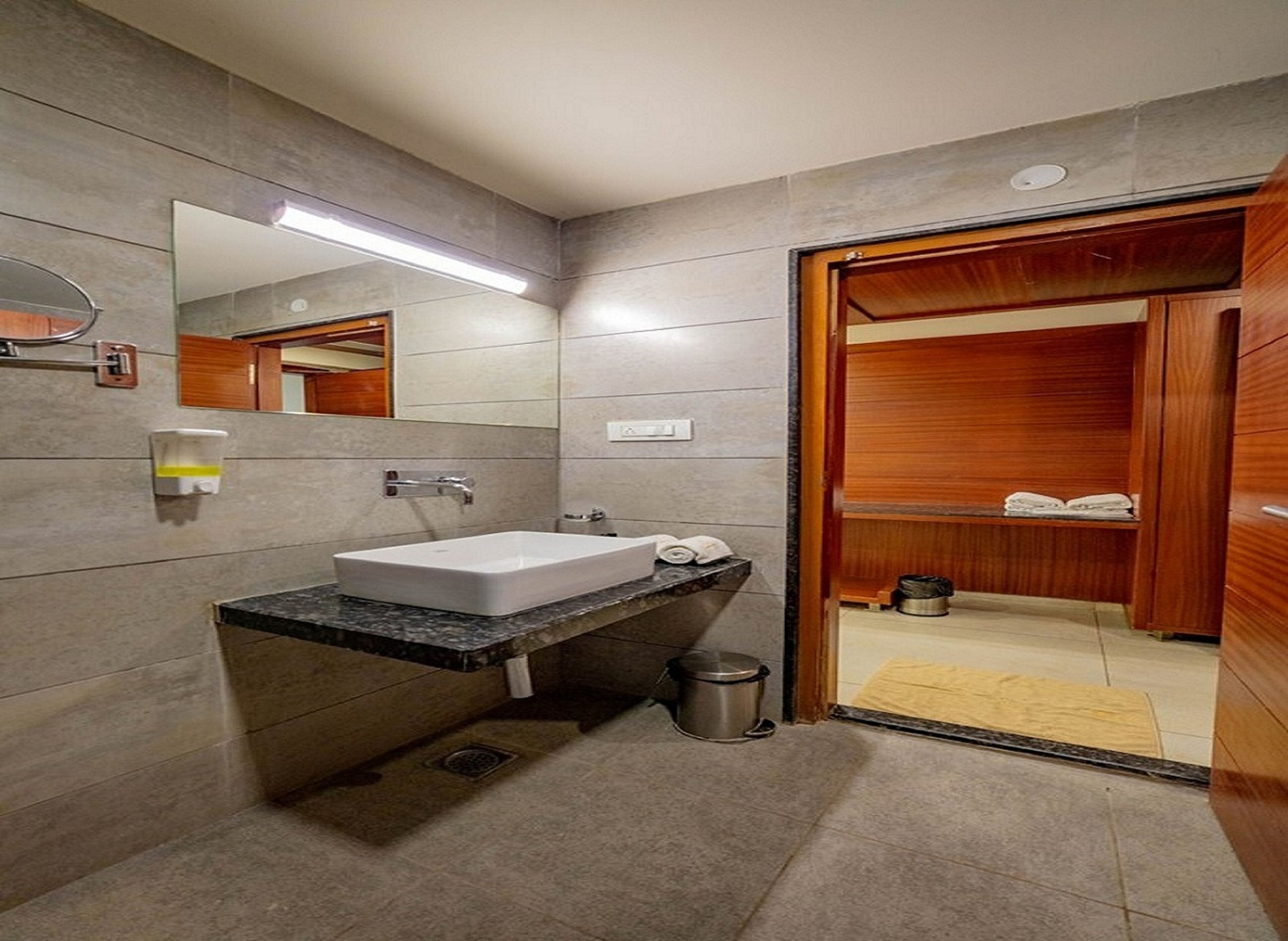 A modern bathroom with a white sink, a mirror, and a wooden vanity.