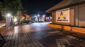 A well-lit entrance to Amarilla Villa with a tiled pathway leading to the building.