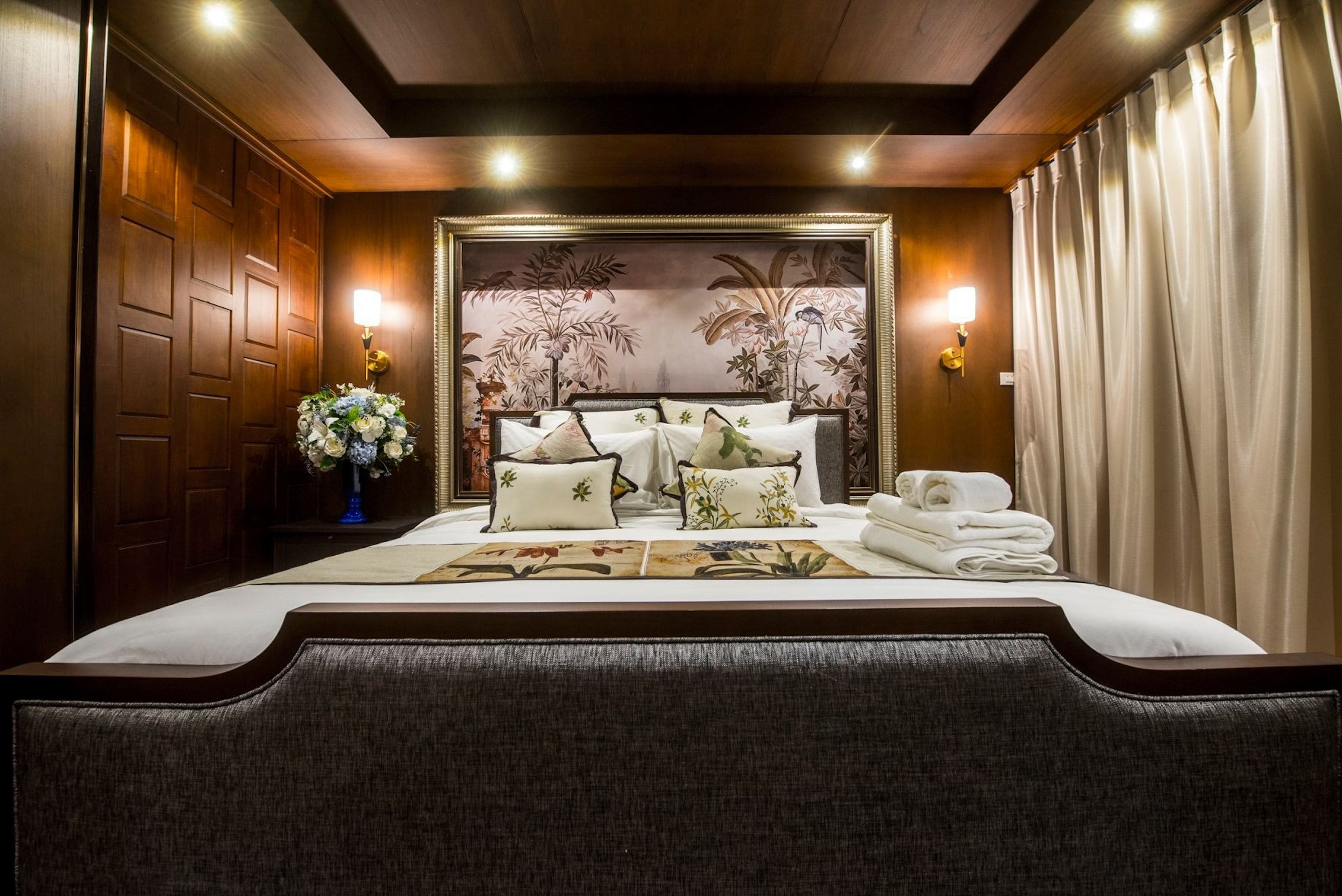 Ein Hotelzimmer mit einem großen Bett, blumigem Wandpapier und zwei Wandleuchten.