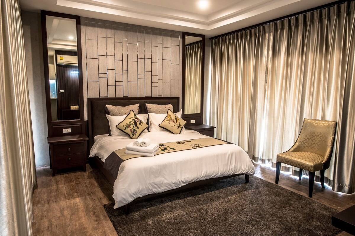 Een hotelkamer met een groot bed, een nachtkastje, een stoel en een wandairconditioning.
