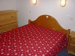 A single bed with a red floral bedspread, a wooden headboard with a heart cutout, and a wooden nightstand with a lamp. - 300m from resort center, 5th floor, view mountain, tv, 50m², Orcières Merlette 1850 (Orcières)
