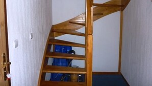 Una escalera en espiral de madera en un pasillo estrecho con alfombra azul.