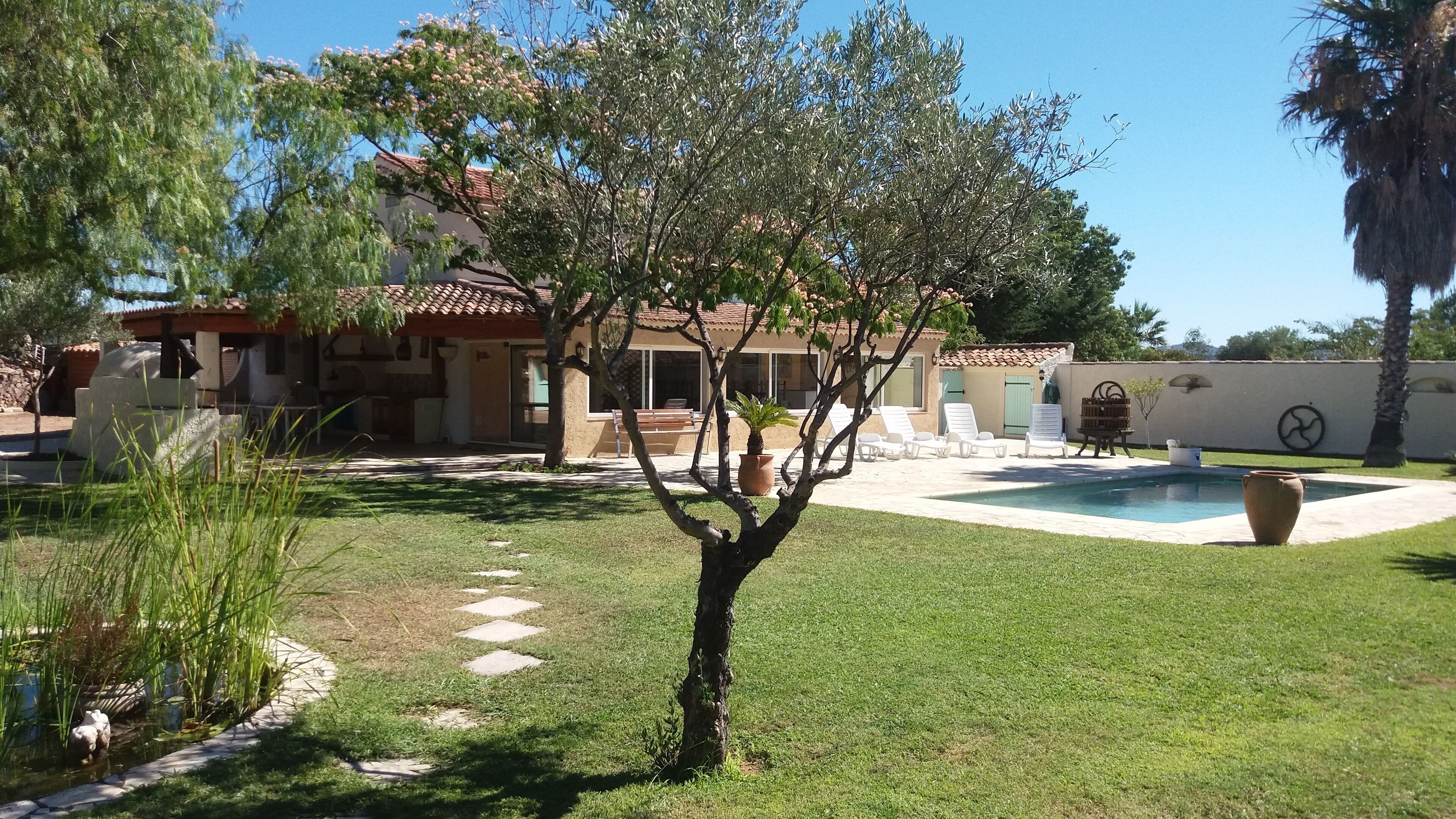 A residential property with a swimming pool, outdoor seating, and a garden area.