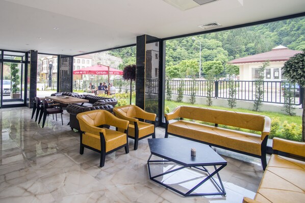 A modern indoor seating area with yellow sofas and a glass coffee table. - Caykara Park Hotel (Çaykara)
