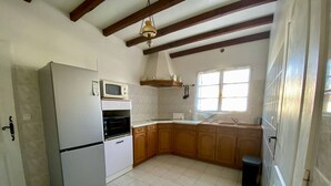 Cocina compacta con refrigerador, microondas, horno y armarios de madera.