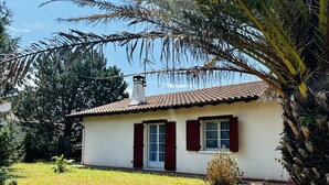 Una casa de un piso con techo de tejas, un pequeño porche y una ventana con contraventanas.