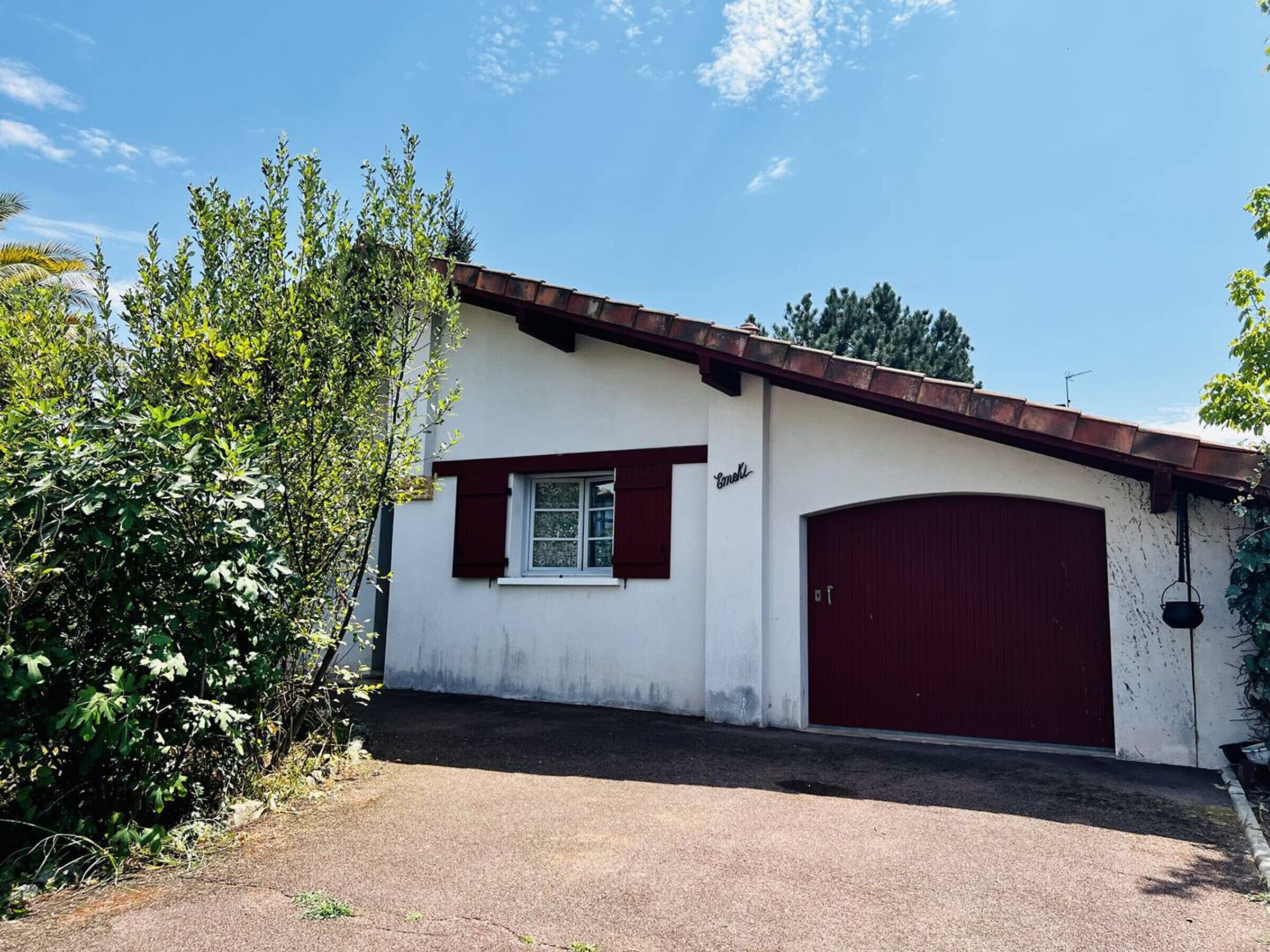 A single-story building with a red garage door and a small window with red shutters.