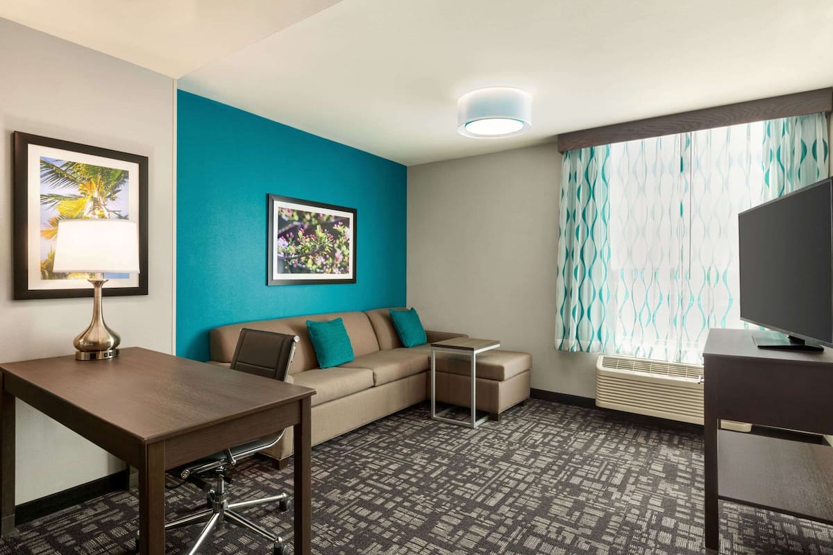 A hotel room with a sofa, a small table, a TV, and a framed picture on the wall.