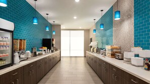 Una cocina moderna con paredes de azulejos azules, electrodomésticos de acero inoxidable y una isla central.